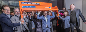 Mitarbeitende des BWGV tragen gemeinsam eine Sitzbanz mit der Aufschrift "Meine Bank gehört mir" und dem Logo der Volksbanken und Raiffeisenbanken.
