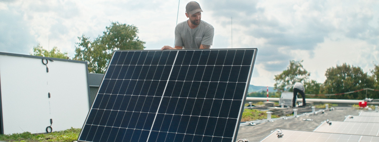 Mann errichtet Fotovoltaik-Modul auf Flachdach