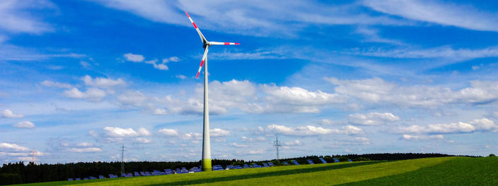 Windräder vor Fotovoltaik-Freiflächenanlage auf grüner Wiese