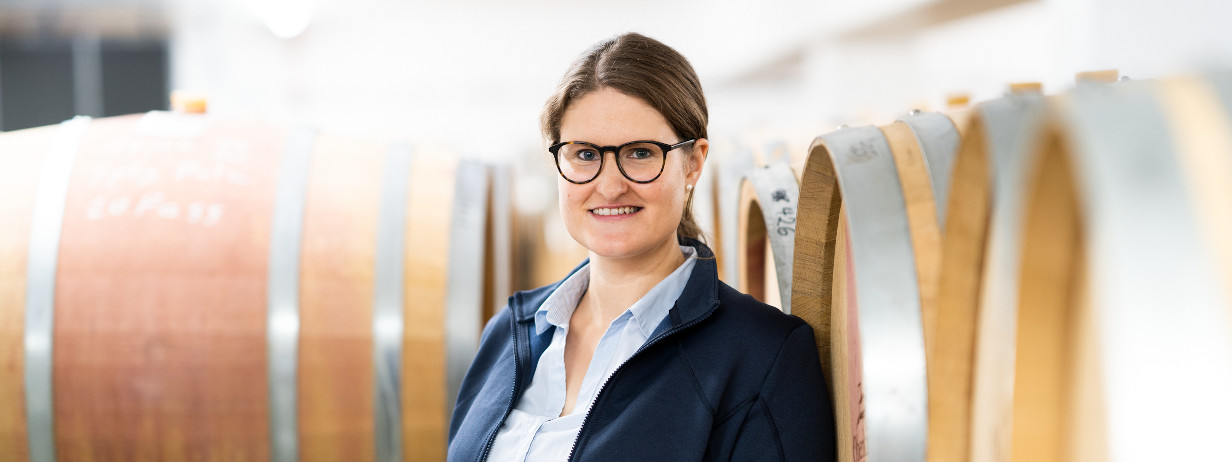 Frau im Business-Look vor hölzernen Weinfässern