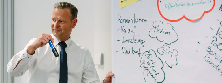 Mann erklärt Begriffe, die auf ein Whiteboard geschrieben sind.